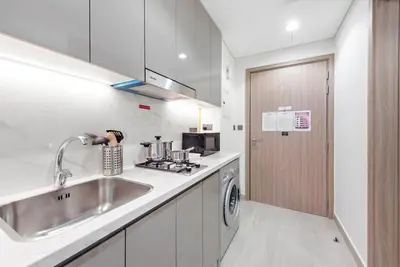a white kitchen with a sink and a dishwasher at FIRST CLASS Studio Sophisticated Getaway in Dubai