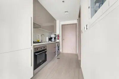 a kitchen with white cabinets and an open door at StoneTree - Fully Furnished - Brand New in Dubai