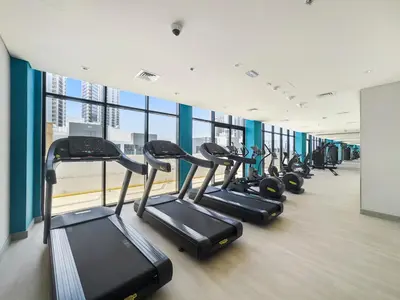 a row of treadmills in a gym with windows at StoneTree - Fully Furnished - Brand New in Dubai