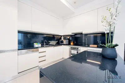 a kitchen with white cabinets and a black counter top at Charming 1BR in The Address Residences Dubai Marina by Deluxe Holiday Homes in Dubai