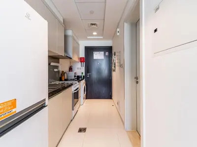 a kitchen with white cabinets and a black door at Studio in Damac Hills - Modern Comfort with Premium Amenities,by Think Realty in Dubai