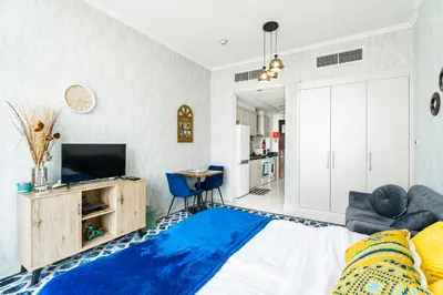 a bedroom with a bed and a tv and a blue rug at Studio in Damac Hills - Luxurious Living with Premium Amenities, by Think Realty in Dubai