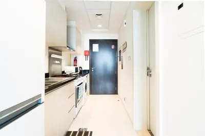 a kitchen with white cabinets and a blue door at Studio in Damac Hills - Luxurious Living with Premium Amenities, by Think Realty in Dubai