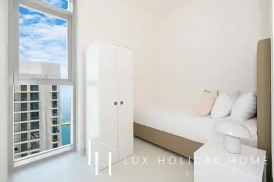 a white bedroom with a bed and a window at LUX The Marina Vista Beachfront Suite 3 in Dubai