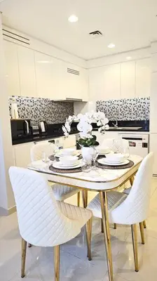 a dining room table with white chairs and a table with flowers at Luxury 3 bedroom Aykon Tower in Dubai