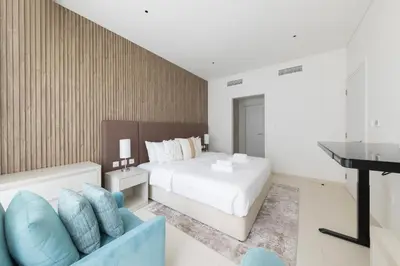 a bedroom with a white bed and a blue couch at Palm Jumeirah 1BR - Rooftop Infinity Pool in Dubai