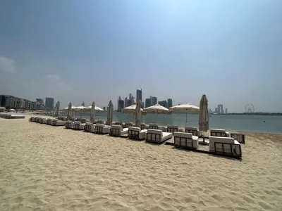 a line of chairs and umbrellas on a beach at Palm Jumeirah 1BR - Rooftop Infinity Pool in Dubai