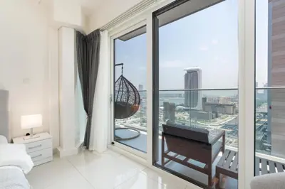 a bedroom with a large window with a swing at Gala Guests - Deluxe Marina View Apartments with Infinity Pool in Dubai