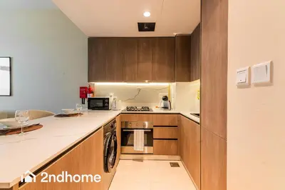 a kitchen with wooden cabinets and a counter top at 2ndHome - Laya Heights, Studio City in Dubai