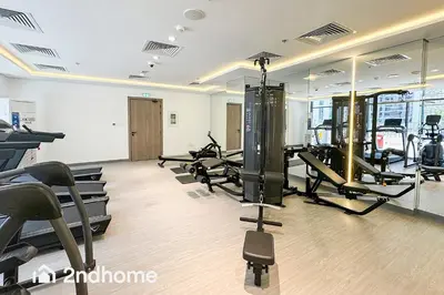 a gym with treadmills and ellipticals in a room at 2ndHome - Laya Heights, Studio City in Dubai