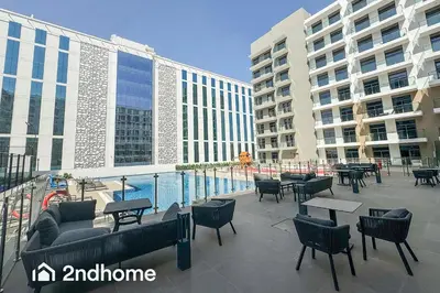 a patio with tables and chairs next to a building at 2ndHome - Laya Heights, Studio City in Dubai