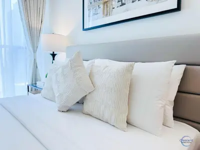 a white bed with white pillows on it at 1BR Downtown Apt Walk to Dubai Mall & Burj in Dubai