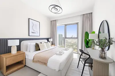 a white bedroom with a large bed and a desk at Silkhaus Elegant 1BDR in Downtown Views II in Dubai