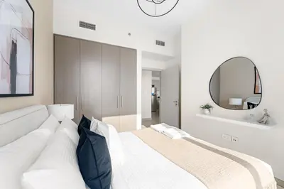 a white bedroom with a large bed with a mirror at Silkhaus Beautiful 1 BDR in Heart of Downtown in Dubai