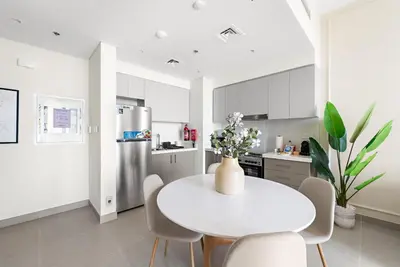 a white kitchen with a white table and chairs at Silkhaus Beautiful 1 BDR in Heart of Downtown in Dubai