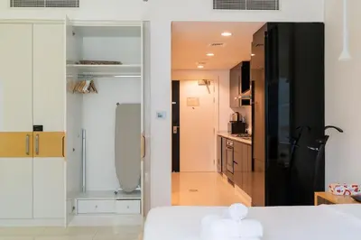 a bedroom with a white bed and a bathroom at Stylish studio with storage room in hotel l Fits 2 in Dubai