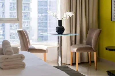 a room with a table with a vase with flowers on it at Stylish studio with storage room in hotel l Fits 2 in Dubai