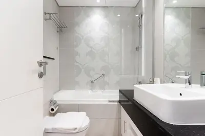 a bathroom with a sink and a tub and a toilet at Stylish studio with storage room in hotel l Fits 2 in Dubai