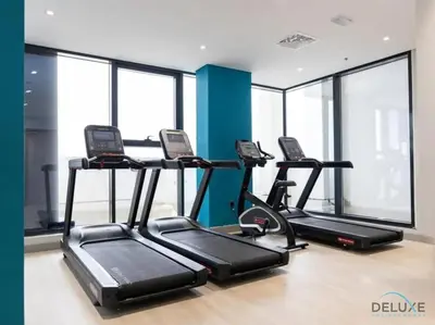 a gym with three treadmills in a room with windows at Stunning 1BR Apartment in Azizi Riviera 42, Al Merkadh by Deluxe Holiday Homes in Dubai