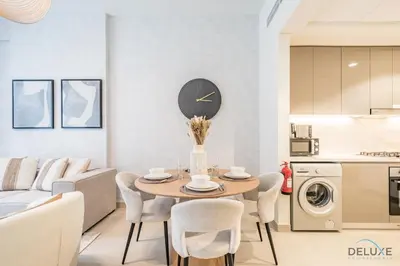 a kitchen and living room with a table and chairs at Stunning 1BR Apartment in Azizi Riviera 42, Al Merkadh by Deluxe Holiday Homes in Dubai