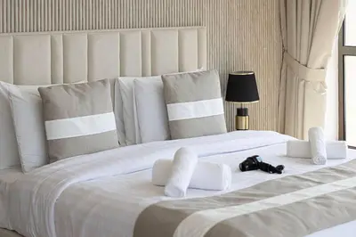 a large white bed with white pillows and a purse on it at Dubai Eye & Sea View, 1-min walk to JBR Beach, Luxurious Beach Retreat! in Dubai