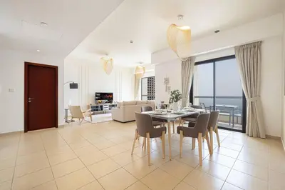 a living room with a table and chairs and a couch at Dubai Eye & Sea View, 1-min walk to JBR Beach, Luxurious Beach Retreat! in Dubai