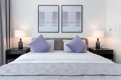 a bedroom with a white bed with purple pillows at Luxury Escapes - Stylish 2BR Apt with City View in Forte Downtown in Dubai