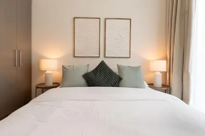 a bedroom with a large white bed with two lamps at Luxury Escapes - Stylish 2BR Apt with City View in Forte Downtown in Dubai