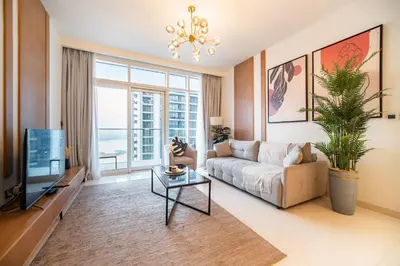 a living room with a couch and a tv at SettlerHomes - Seaside Lux Marina near Private Beach in Dubai