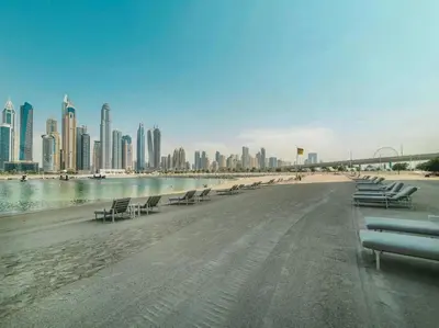 a beach with chairs and buildings in the background at SettlerHomes - Seaside Lux Marina near Private Beach in Dubai