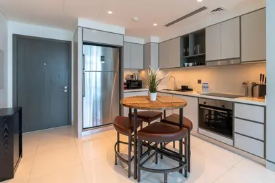 a kitchen with a table and two stools at 2 BR Private Beach Access & Marina View in Dubai