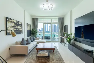 a living room with a couch and a tv at 2 BR Private Beach Access & Marina View in Dubai
