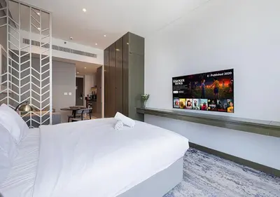 a bedroom with a white bed and a flat screen tv at Lux Studio in Downtown - Damac Maison Prive - Near Burj Khalifa in Dubai