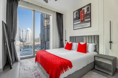a bedroom with a bed with red pillows and a large window at the London Condo - Forte Downtown Dubai in Dubai