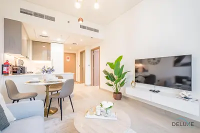 a living room and kitchen with a table and chairs at Inviting 1BR Apartment in Azizi Riviera 32, Al Merkadh by Deluxe Holiday Homes in Dubai