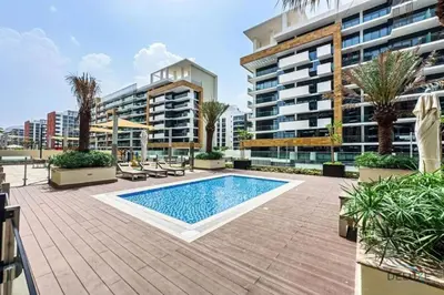 an outdoor swimming pool with palm trees and buildings at Inviting 1BR Apartment in Azizi Riviera 32, Al Merkadh by Deluxe Holiday Homes in Dubai