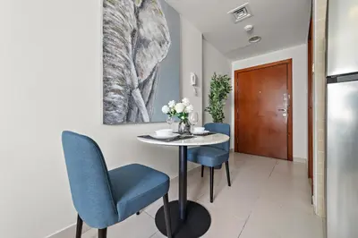 a dining room with a table and blue chairs at StoneTree - Newly Furnished - Near Metro in Dubai
