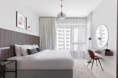 a white bedroom with a large bed and a desk at Your 2BR with Burj Khalifa View in Dubai