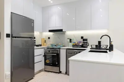 a kitchen with stainless steel appliances and white cabinets at 1-Bed in Binghatti Crescent, Next to Circle Mall in Dubai