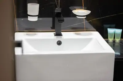 a white sink with two cups on top of it at 1-Bed in Binghatti Crescent, Next to Circle Mall in Dubai