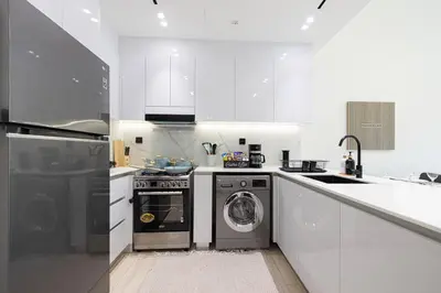 a white kitchen with a washer and dryer in it at 1-Bed in Binghatti Crescent, Next to Circle Mall in Dubai
