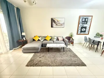 a living room with a couch and a table at Lavender Oasis - Entire Spacious 1 flat in Jumeirah Village Circle in Dubai