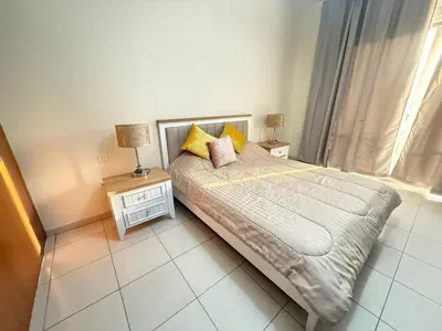 a bedroom with a bed and two night stands and a window at Lavender Oasis - Entire Spacious 1 flat in Jumeirah Village Circle in Dubai