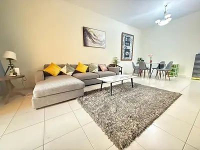 a living room with a couch and a table at Lavender Oasis - Entire Spacious 1 flat in Jumeirah Village Circle in Dubai
