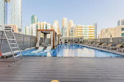 a large swimming pool with chairs and buildings at Cozy 2 bedroom apartment in Dubai Marina in Dubai