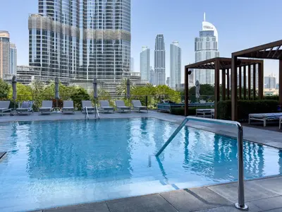 a large swimming pool with chairs and a city skyline at Escape24 2BR in Address Opera with Skyline Views near Burj Khalifa in Dubai