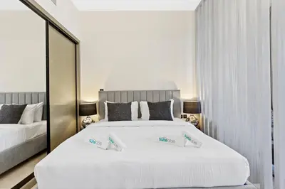 a bedroom with a large white bed and a mirror at Studio Retreat with Canal and Burj Khalifa Views in Dubai