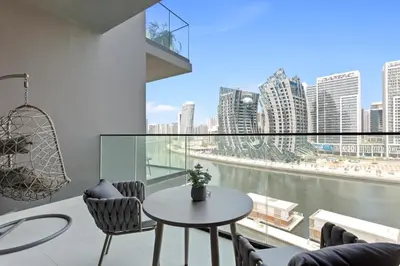 a balcony with a table and chairs and a large window at Studio Retreat with Canal and Burj Khalifa Views in Dubai