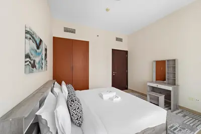 a bedroom with a large white bed and a desk at StoneTree - Stunning Lake View - Spacious in Dubai