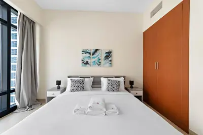 a white bedroom with a large white bed and a window at StoneTree - Stunning Lake View - Spacious in Dubai